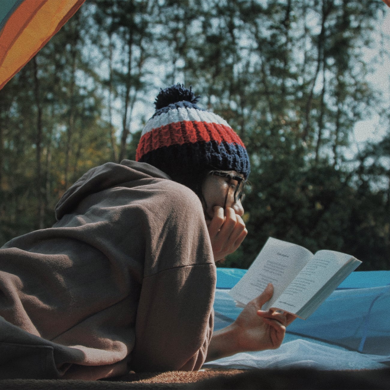Woman reading book from inside tent