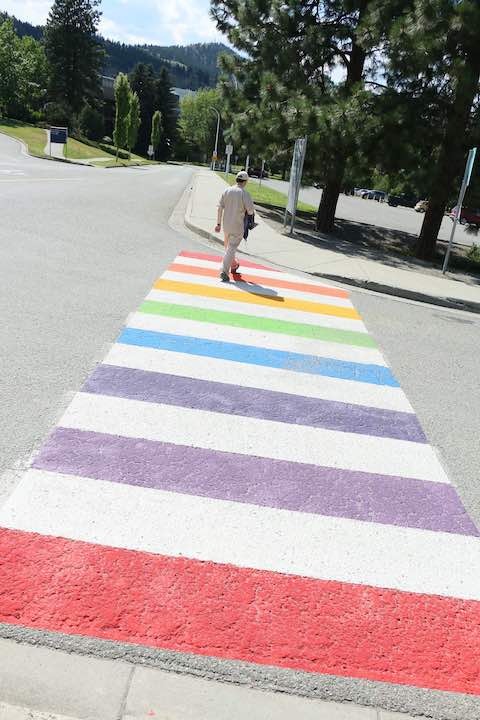 person crossing rainbow crosswalk