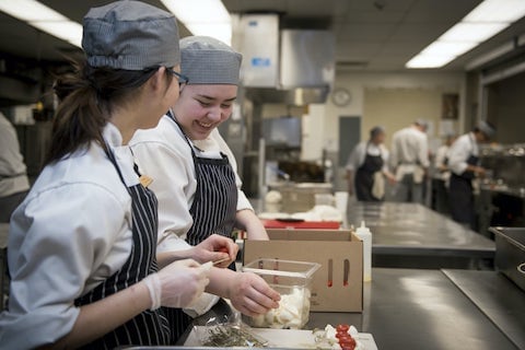 Culinary arts students preparing food and smiling