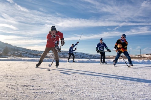 people playing hockey outdoors on a frozen lake