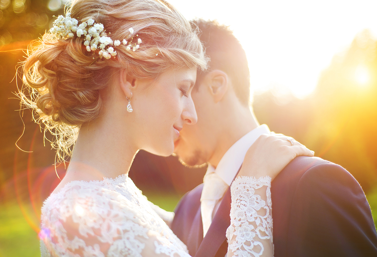 Photo of young wedding couple enjoying romantic moments outside in a summer meadow
