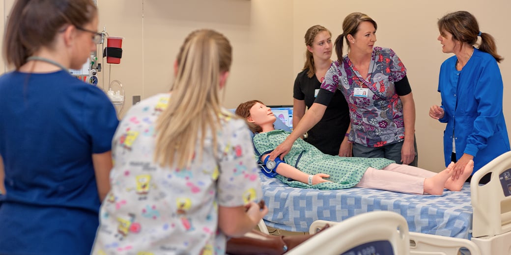 Nursing instructor showing students how to take blood pressure