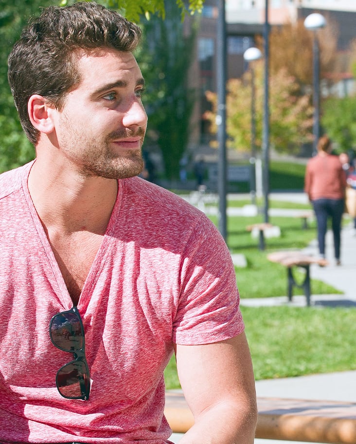 Male student sitting on campus bench