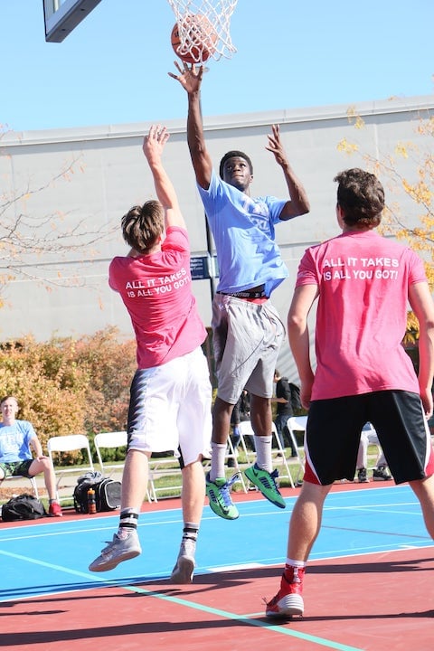 students playing basketball on outdoor court at campus