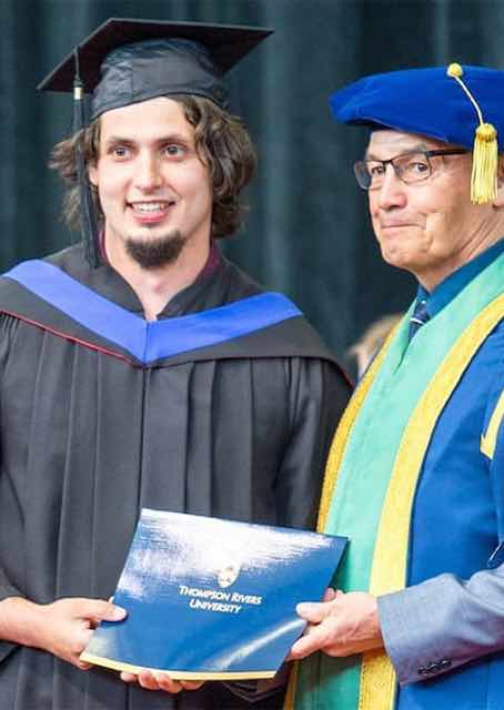 Graduate posing with Chancellor at Convocation
