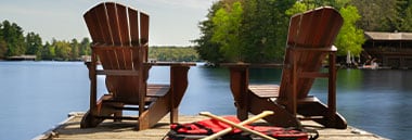 two empty chairs at end of dock on lake