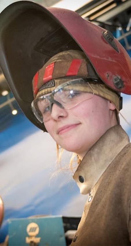 Student welder smiling at camera